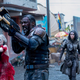 Harley Quinn, Bloodsport, Ratcatcher, and Polka-Dot Man stand on a devastated street with weapons raised.
